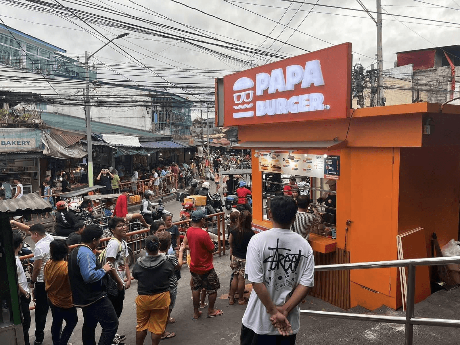 A Papa Burger branch on a busy street with people walking past.