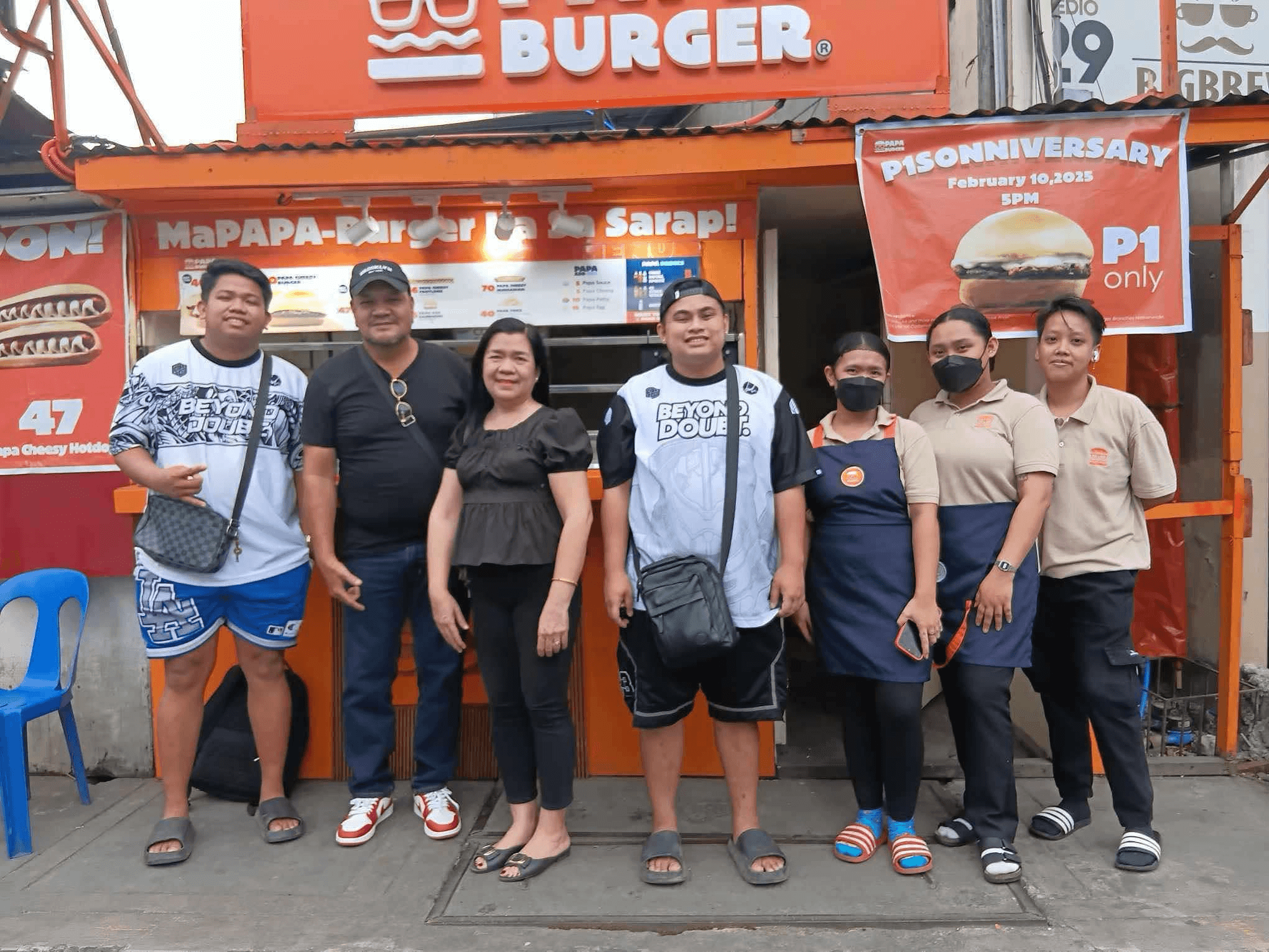A group standing together in front of a Papa Burger branch.