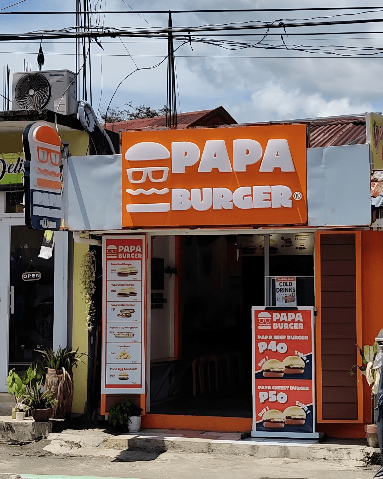A Papa Burger storefront with its menu boards under the signage.