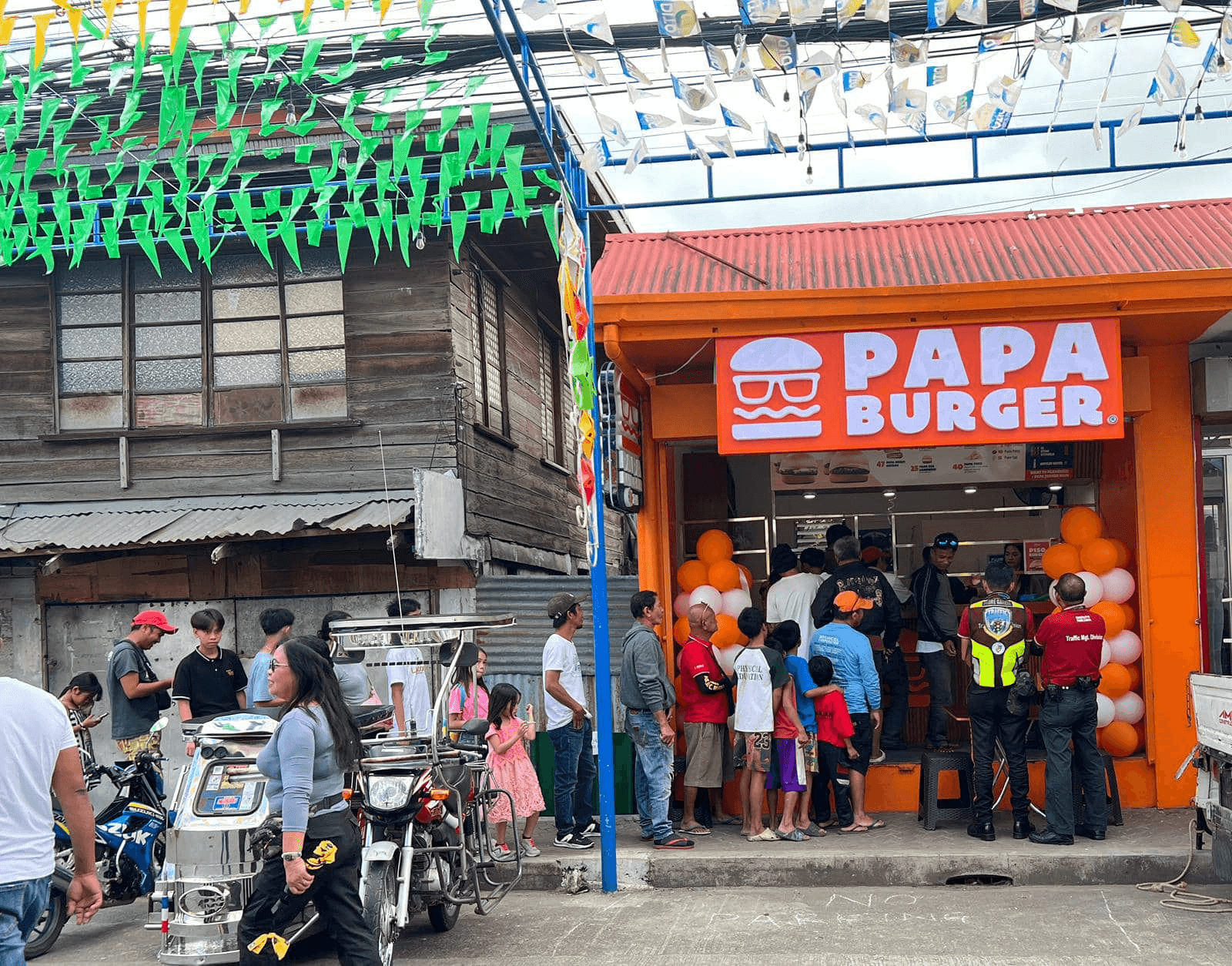 A Papa Burger branch during a local fiesta, buntings strung overhead.
