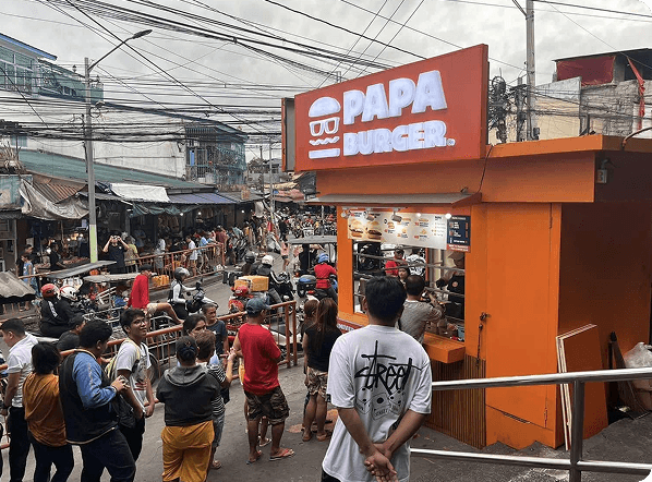 A Papa Burger branch on a busy street, with customers waiting at the counter.